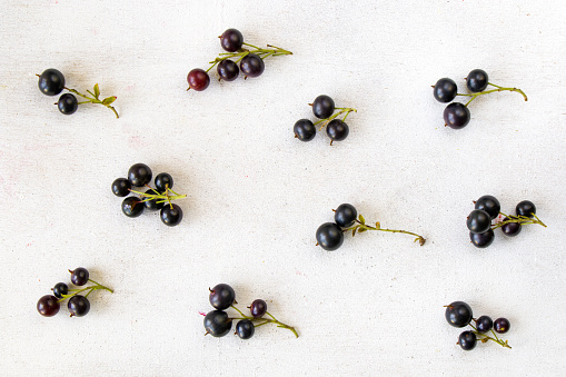 An overhead shot of currants separated and placed on a white surface