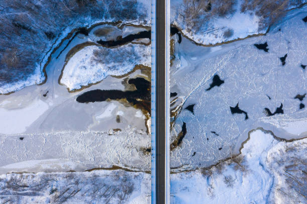 istock Top view of a curvy road over a flowing river through the snow-covered forest 1436962499