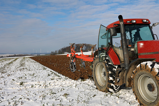 A view of a tractor at work plowing a field during winter