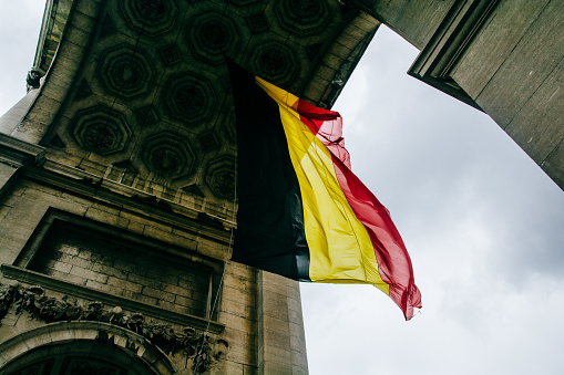 A low angle shot of the Belgium flag under the Arcade du Cinquantenaire