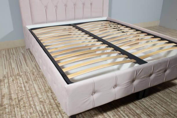 istock Bed with light pink upholstery and without mattress in an empty room 1436965067
