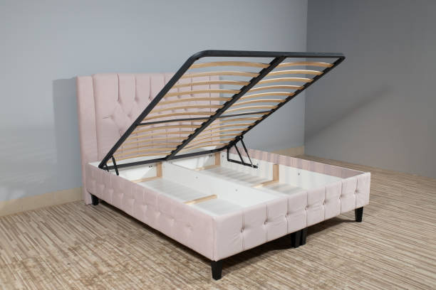 istock Bed with light pink upholstery, without mattress and with opened storage in an empty room 1436965070