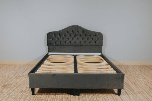 istock Bed with gray upholstery and without mattress in an empty room 1436965073