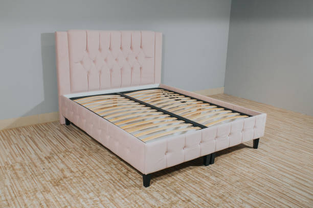 istock Bed with light pink upholstery and without mattress in an empty room 1436965076