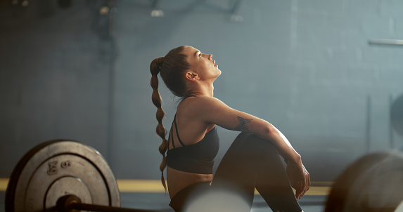 Fitness, break and tired, exercise routine and woman in gym, weight lifting and active lifestyle training. Health and wellness motivation, rest after workout and strength, endurance and to be fit.