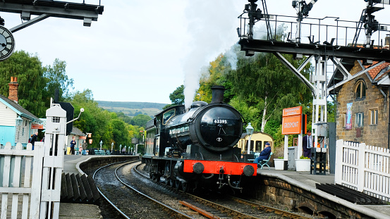 Grosmont, North Yorkshire, UK - 26th September, 2022: Old-fashioned steam trading pulling out of Grosmont station, Yorkshire. The North Yorkshire steam railway is a popular tourist attraction for visitors from all over the country.