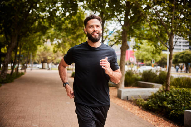 Smiling man listing to music on earbuds during a park run