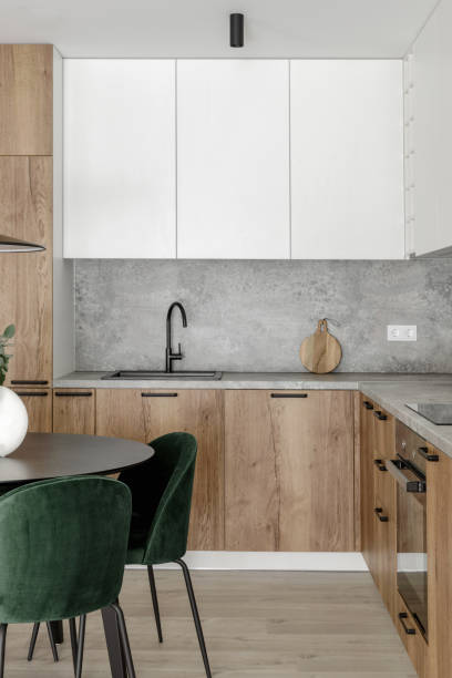 istock Modern minimalistic kitchen and dining room interior with wooden and white surfaces, green chairs and eucalyptus in ceramic vase. Aesthetic simple interior design concept. 1436971493