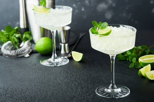 istock Margarita cocktail with lime, tequila, mint and ice on dark table with amazing backlight, copy space. Classic Margarita or Daiquiry Cocktail. Bar card or counter concept. Selective or soft focus. 1436971574