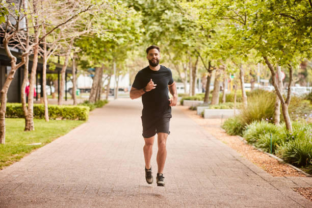 istock Fit young man listing to music on earbuds during a park run 1436972078