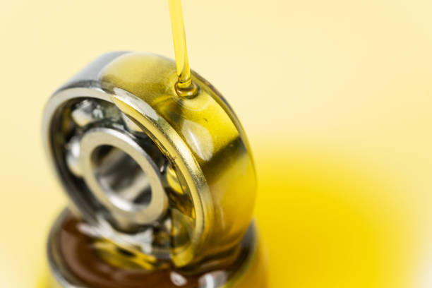 closed up macro, pouring automotive engine oil into ball bearing isolated on yellow oil background with copy space, engineering and industrial concept. motor oil on bearing - vehicle part car part of ball bearing imagens e fotografias de stock