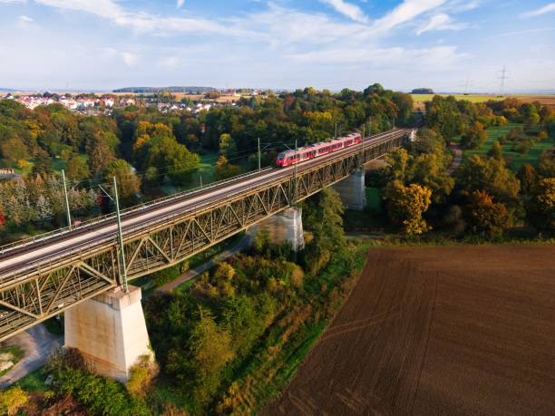 istock Aerial view of train in motion on bridge surrounded by dense trees 1436973217