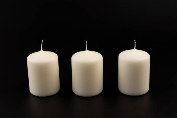 istock White candles on dark background. Close-up, copy space. 1436973776