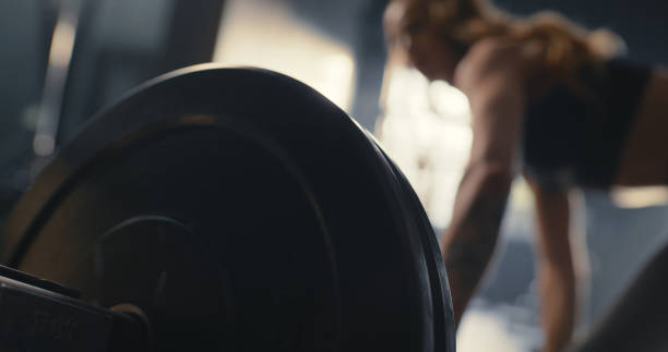 Woman in gym, weightlifting for fitness training arm muscles and healthy lifestyle. Closeup of floor workout equipment, strong bodybuilder athlete start heavy challenge and exercise with barbell mujer en gimnasio, levantamiento de pesas para el entrenamiento físico de los músculos del brazo y estilo de vida saludable. primer plano del equipo de entrenamiento, el atleta culturista fuerte comienza el desafío pesado y el ejercicio de peso muerto c