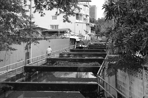 Senior woman walking by a canal in the Thonburi district of Bangkok, Thailand.