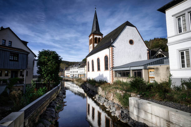 the romantic evangelical trinity church reflected in the urft river in the german eifel town gemuend