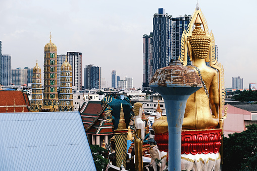 Bangkok skyline contrasts with the large Buddha images at Wat Khunchan, in Thonburi district, Thailand.