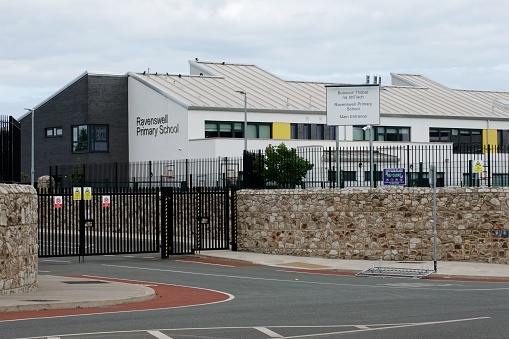 Bray, Ireland – August 06, 2022: Ravenswell Primary School building seen across an empty street on cloudy summer day.