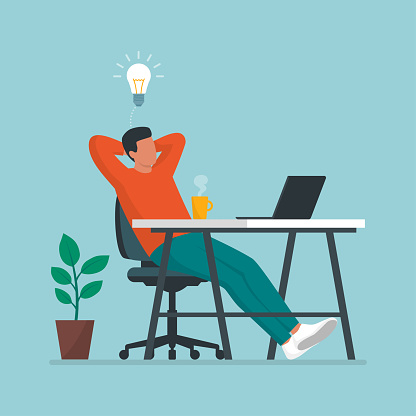 Creative man sitting at desk and taking a break, he is relaxing with hands behind head and having a good idea