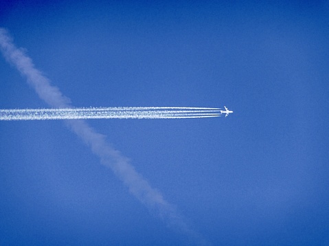 Flugzeug mit Kondensstreifen hoch am Himmel