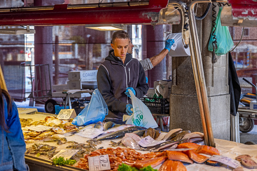 Venice, Italy - October 12th 2022: Fish vendor working at the open air fish market in the center of the old Italian city Venice