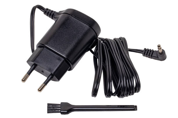 白い背景に充電式のひげとバリカン、クリーニングブラシ用の黒いac-dc電源アダプターまたは充電器の接写。マクロ。 - mobile phone charging power plug adapter ストックフォトと画像