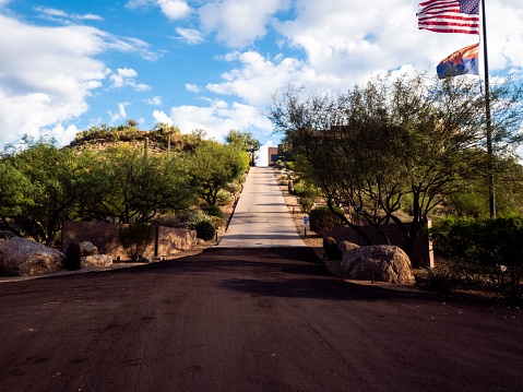 A picturesque shot of a newly built road with the flag of America and Arizona under blue sky