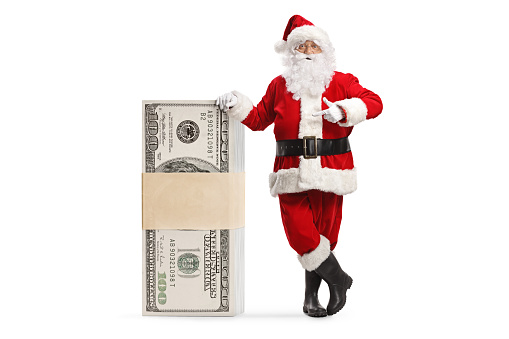 Santa claus leaning on a stack of money and pointing isolated on white background
