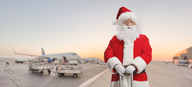 Santa claus standing with a suitcase standing on an airport apron