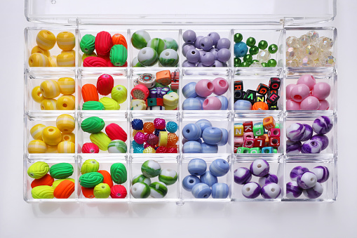 Plastic organizer with different beads on white background
