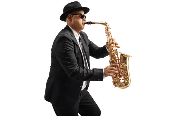 Man in formal suit, tie, sunglasses, bowler hat, holding trumpet, on country road
