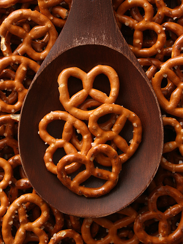 Top view of wooden spoon with salty snack pretzels on and beneath it
