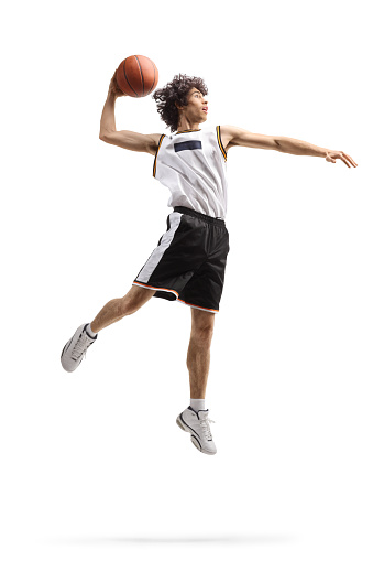 Full length shot of a basketball player up in the air in a slam dunk pose isolated on white background