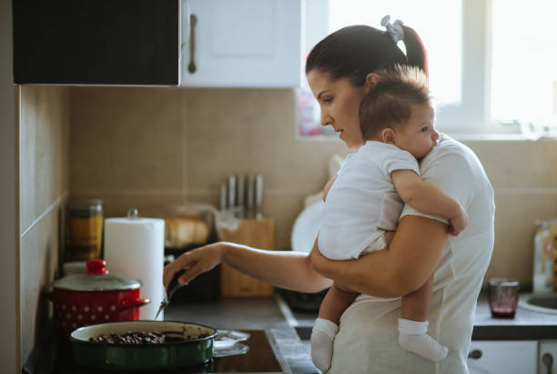 istock Mother holding her baby while preparing lunch 1436996007