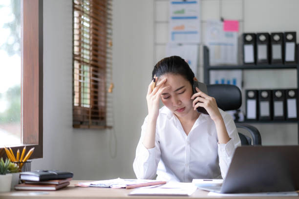 istock Serious asian businesswoman using laptop looking at computer talking on phone consult client sit at desk, focused female sales manager make mobile business call discuss work with customer in office 1436996979
