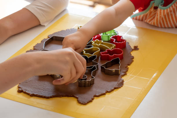 istock Selective focus. Kids making gingerbread cookies with various Christmas cookie cutters. Gingerbread dough. Family Christmas fun moments 1436997564