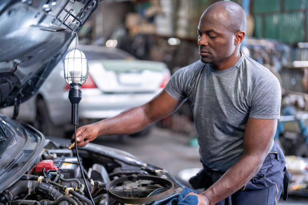istock Mechanical guy at car repair shop stand pulling engine oil dipstick 1436998128