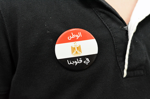 A T Shirt badge of a young child with the Egyptian flag with an Arabic inscription, Translation of Arabic text (Egypt Homeland is in our hearts), national Egyptian flag with its 3 colors red, white and black