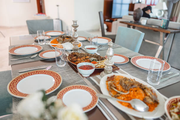 Dining table is full of traditional middle eastern food. There are tableware, cutlery and white plates with orange and red details around it.