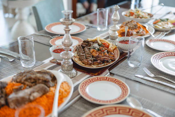 Brown dining table full of delicious traditional middle eastern cuisine. There are grey placemats, silver cutlery. Beautiful setting.
