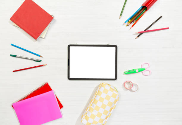 istock smart tablet around books, notebook and pens on white desk 1437003070