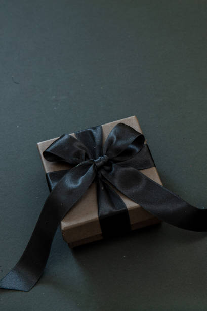 istock Black Friday Sale concept. Gift box with black ribbon isolated on black. 1437005292