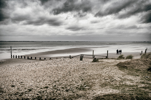 This family have wrapped up warm before they have braved the beach in winter. The pebbles and dunes will be hard work on the feet, and the gathering clouds promise a winter downpour very soon.