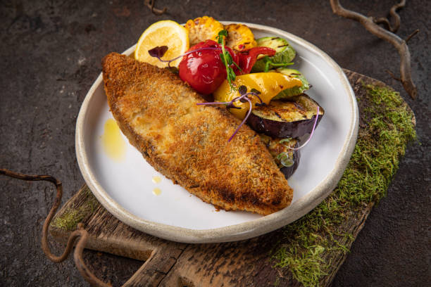 istock fish and white plate, fried fish fillet and vegetables on black background. 1437008919