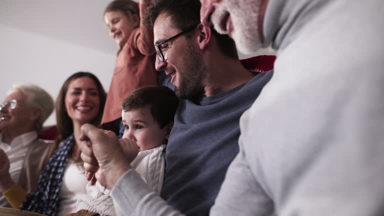 Cheerful extended family watching soccer game on TV at home.