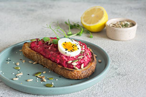 istock Whole grain toast with beetroot hummus, seeds, egg and microgreens (sprouted pea sprouts) on a light gray background. The concept of healthy eating.. 1437011627
