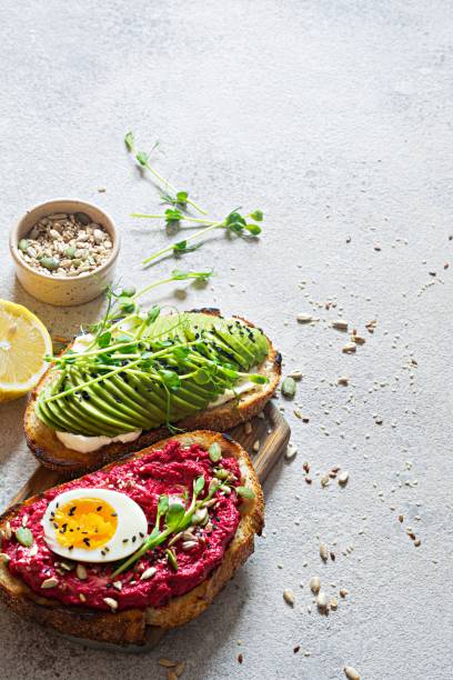 istock Whole grain toast with cream cheese, avocado, beetroot hummus, seeds, egg and microgreens (sprouted pea sprouts) on a light gray background. Healthy food concept. 1437011677