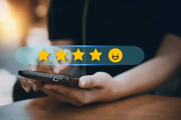 Photo of review rating and feedback 5 stars, the best and excellent admire by reviewer, close up on customer hand pressing on smartphone screen with gold five star