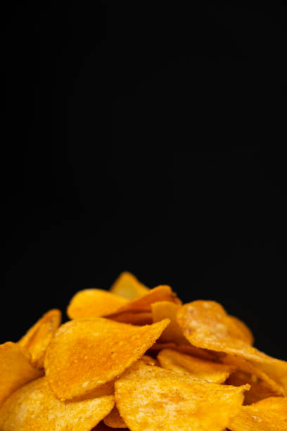 istock Delicious crispy potato chips with spices on a black background, place for text 1437015476