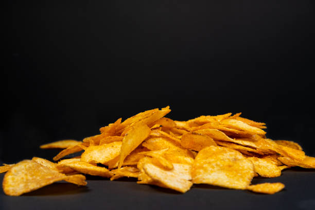 istock Delicious crispy potato chips with spices on a black background, place for text 1437015506